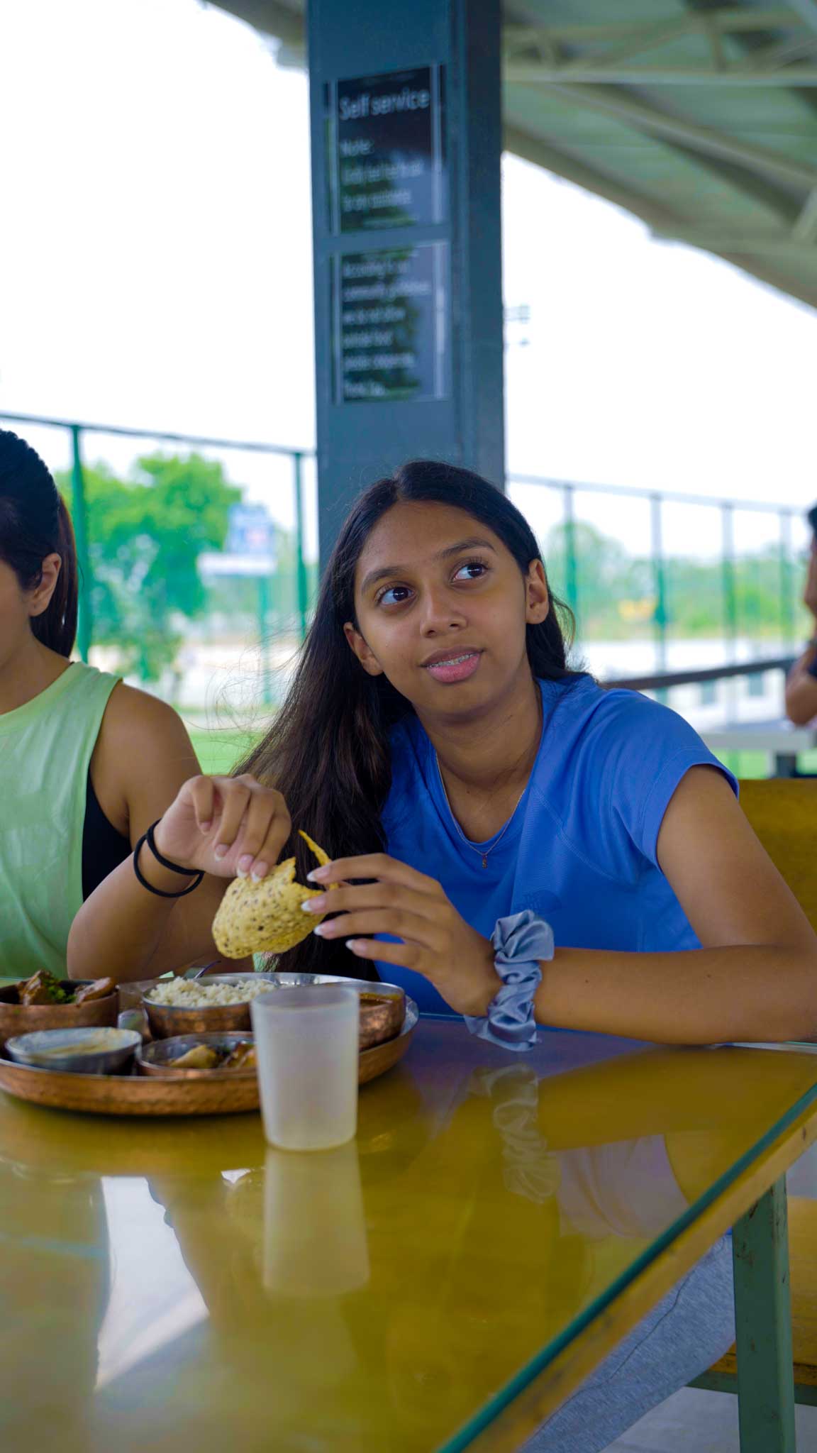 Young girl eating a meal at the dining area during a family playcation at the sports center.